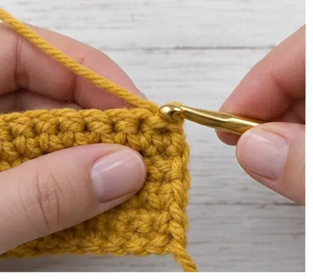 Hook approaching the final mustard crochet stitch before a color change