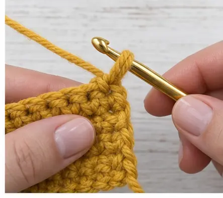 Mustard yarn being pulled up through the last crochet stitch