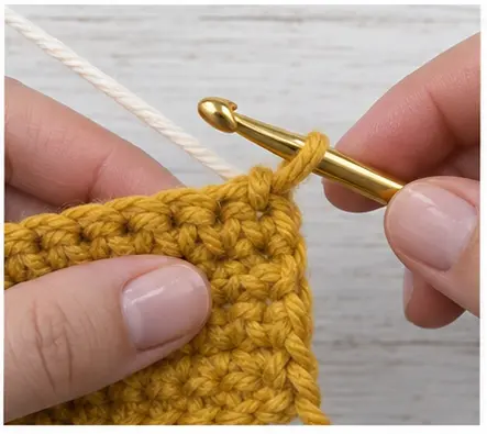 Cream yarn positioned over the hook for a clean crochet color change