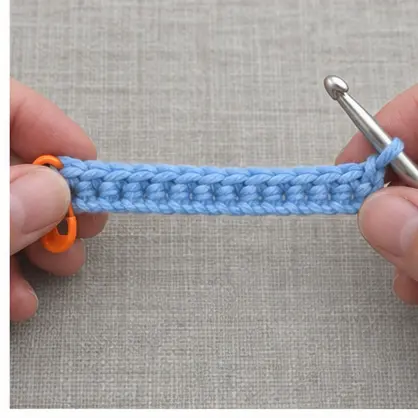 Completed first blue crochet row with markers at both ends