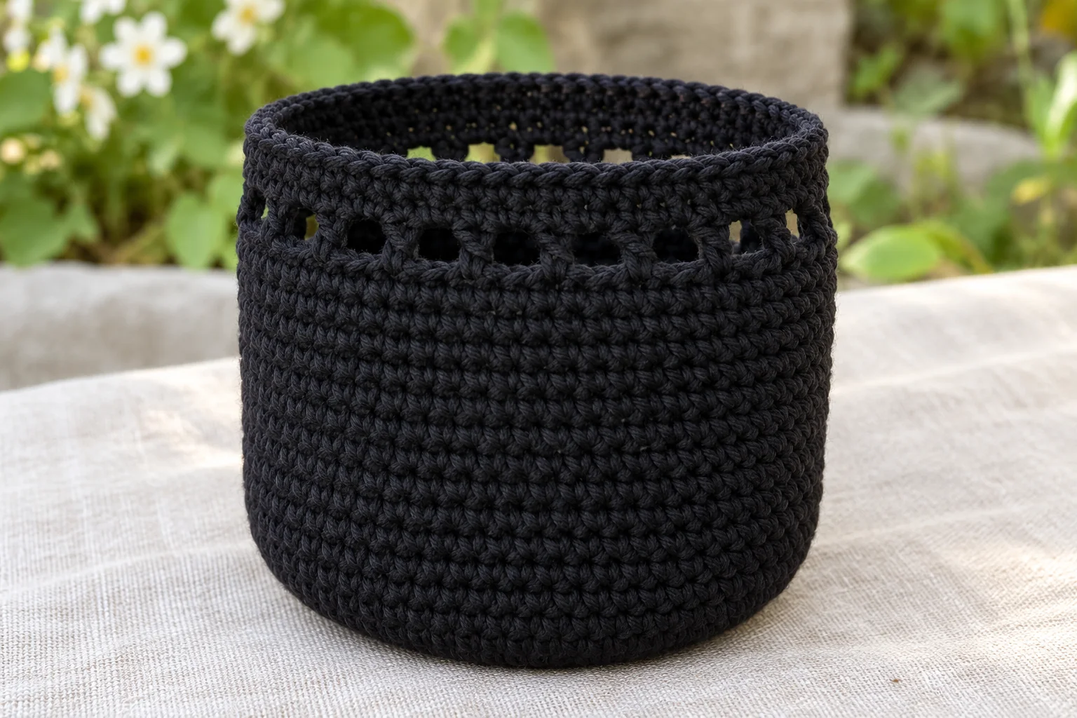 Drawstring eyelets around the top of the black crochet pouch