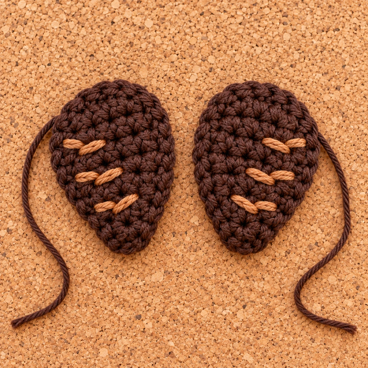 Two brown crochet turkey wings with decorative embroidered lines